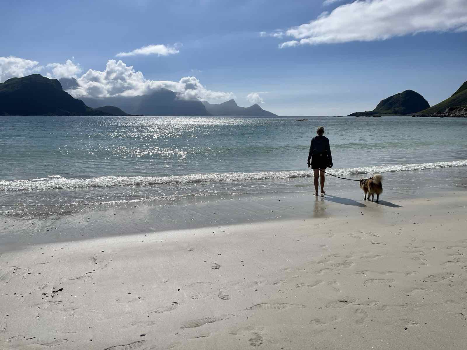 Annelies wandelt met haar hond aan de leiband op een strand in Noorwegen